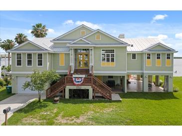 Inviting waterfront home with a lush lawn, yellow door, and elevated architecture at 291 River Rd, Oak Hill, FL 32759