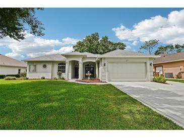 Charming single-story home featuring lush green lawn, manicured landscaping, and a welcoming entrance with decorative fountain at 5453 Grove Mnr, Lady Lake, FL 32159