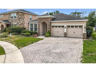 Charming home with a two car garage, brick driveway, stone accents, and landscaped front yard at 13842 Pickett Reserve Ct, Orlando, FL 32826