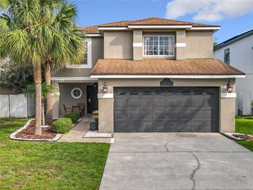 Inviting home featuring a well-manicured lawn, mature palm trees, and a two-car garage at 1803 Meadow Pond Way, Orlando, FL 32824