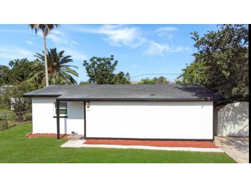 Side view of a white home with a dark roof and a well-maintained lawn at 49 Orange Park Blvd, Lake Wales, FL 33898