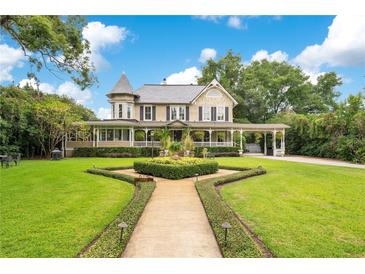 Beautiful two-story home with manicured lawn, mature trees, and a charming walkway with attractive landscaping at 614 Lake Ave, Orlando, FL 32801