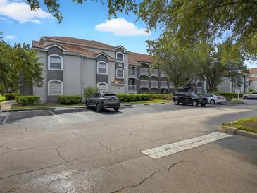 Two-story condo building with gray facade, balconies, and ample parking at 13917 Fairway Island Dr # 931, Orlando, FL 32837