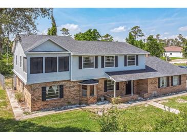 Two-story home featuring brick and siding exterior, a gray roof, dark shutters, and a well-maintained lawn at 1601 Randolph St, Deltona, FL 32725