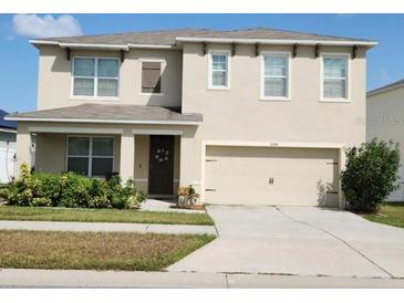 Two-story home featuring a two-car garage, neutral stucco, well manicured landscaping, and decorative shutters at 3074 Royal Tern Dr, Winter Haven, FL 33881