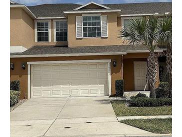 Inviting townhouse featuring a two-car garage and lush landscaping at 3308 Rodrick Cir, Orlando, FL 32824
