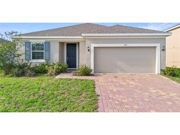 Charming single-Gathering home featuring a two-car garage, brick driveway, and well-maintained lawn at 417 Tisone Ln, Davenport, FL 33837