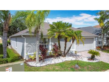Well-maintained home with a brick driveway, manicured lawn, and tropical landscaping featuring palm trees at 4611 Cumbrian Lakes Dr, Kissimmee, FL 34746