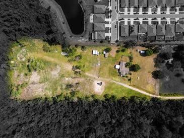 An aerial view of a spacious property with ample land, located near a serene lake and modern homes at 5365 Rambling Rd, St Cloud, FL 34771