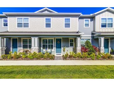 Charming two-story townhome featuring a quaint front porch, blue door, and landscaped front yard at 625 Dogfish Ln, Debary, FL 32713