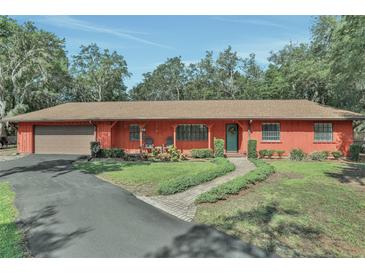 Charming single-story home featuring a lush front yard, covered porch with seating, and an attached garage at 127 Oak Ln, Ormond Beach, FL 32174