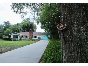 Charming single-story home featuring a brick chimney, turquoise trim, and a well-manicured front yard at 1405 Periwinkle Ave, Deland, FL 32724