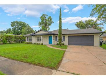 Charming single-story home featuring a well-manicured lawn, a blue front door, and an attached two-car garage at 3902 Brandeis Ave, Orlando, FL 32839