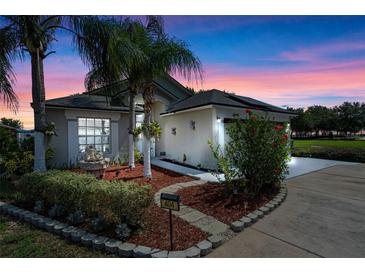 Charming home with lush landscaping, palm trees, and a paver walkway leading to the front door at 404 Obo Dr, Davenport, FL 33896