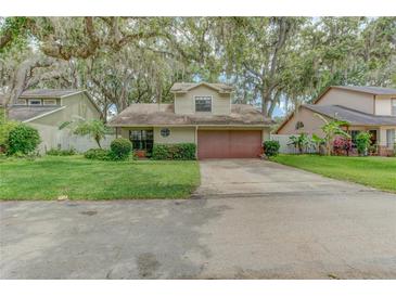 Charming home featuring a two-car garage, lush landscaping, and mature trees draped with Spanish moss at 9948 Timber Oaks Ct # 14, Orlando, FL 32817