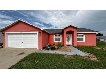 Charming single-Gathering home featuring a two-car garage and a well-maintained front yard landscape at 113 Kaigen Ct, Haines City, FL 33844