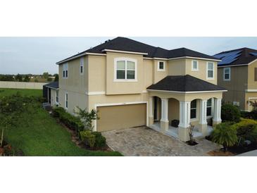 Two-story home featuring a brick paved driveway and a tan exterior at 1544 Nassau Point Trl, Kissimmee, FL 34747