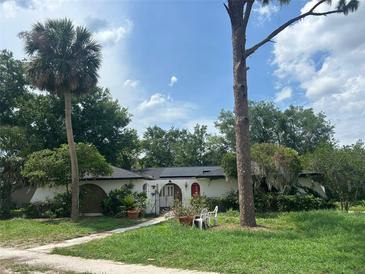 Charming single-story home with white stucco and lush landscaping at 219 Sheridan Ave, Longwood, FL 32750