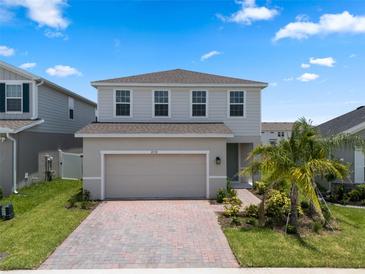 Charming two-story home with a brick-paved driveway, lush landscaping, and attached two car garage at 2372 Orchid Dr, Davenport, FL 33837