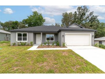Charming single-story home featuring a well-maintained lawn, neutral paint, and an attached two-car garage at 327 Larch Rd, Ocala, FL 34480