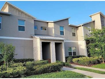 Modern two-story townhouse featuring a neutral color scheme, well-maintained landscaping, and a welcoming covered entrance at 456 Ocean Course Ave, Davenport, FL 33896