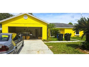 Bright yellow house with an open garage, set on a sunny day in a community at 4719 Miranda Cir, Orlando, FL 32818
