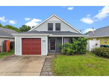 Charming home with a red garage door, inviting front porch, and lush landscaping at 1413 Brookebridge Dr, Orlando, FL 32825