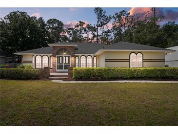 Inviting single-story home featuring arched windows, brick accents, and a well-manicured lawn at 14612 Bray Rd, Orlando, FL 32832