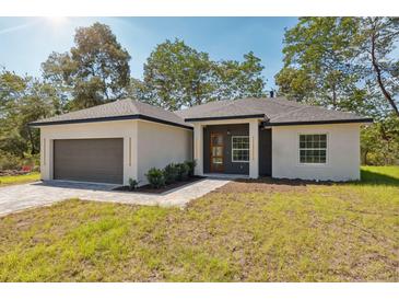 Charming single-story home featuring a gray brick walkway, a two-car garage, and well-manicured landscaping at 14930 Sw 66Th Ave Rd, Ocala, FL 34473