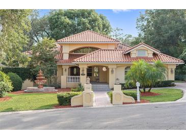 Charming two-story home featuring a red tile roof, meticulously landscaped yard, and inviting fountain feature at 1542 Islay Ct, Apopka, FL 32712