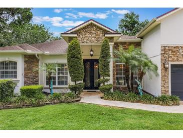 Beautiful front entrance with stone accents, manicured landscaping, and a custom iron door at 1874 Royal Majesty Ct, Oviedo, FL 32765