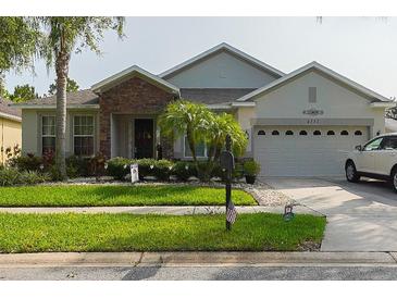 Charming single-story home featuring a stone facade, well-manicured lawn, and attached two-car garage at 2237 Osprey Woods Cir, Orlando, FL 32820
