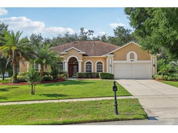 Inviting one-story home featuring a manicured lawn, mature trees, and charming architectural details at 604 Cheviot Ct, Apopka, FL 32712