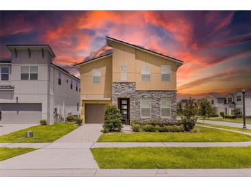 Beautiful two-story home featuring stone accents, well-manicured landscaping, and a brick-paved driveway at 1809 Tropical Palms Cir, Kissimmee, FL 34747