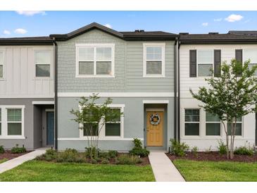 Charming townhome with a welcoming yellow front door and fresh, modern landscaping at 3256 Merton Aly, Orlando, FL 32808