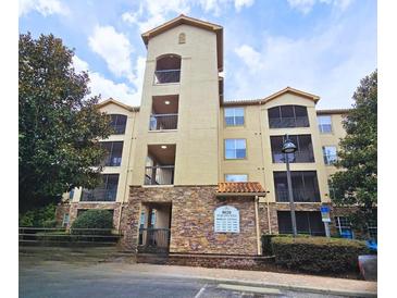 Multi-story condo building with stone facade, balconies and lush surrounding trees at 8020 Tuscany Way # 6307, Davenport, FL 33896