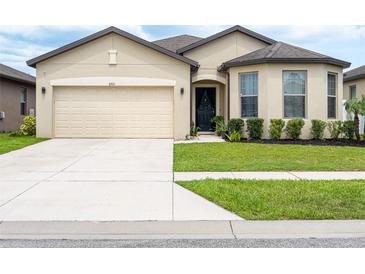Charming single-story home with a two-car garage, manicured lawn, and decorative front door wreath at 8710 Rindge Rd, Polk City, FL 33868