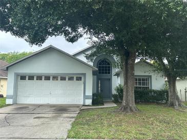 Charming single-story home featuring a two-car garage, arched window, and mature landscaping at 11606 Goodwyck Dr, Orlando, FL 32837