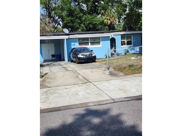 Modest blue home featuring a long driveway with a car parked in front at 1245 Emeralda, Orlando, FL 32808