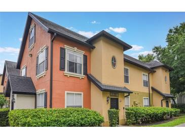 Two-story townhome showing stucco exterior, black trim, well-maintained landscaping, and a blue sky background at 6001 Westgate Dr # 2124, Orlando, FL 32835