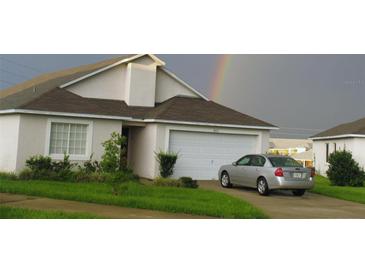 Charming home with a two-car garage, landscaped front yard and a rainbow behind at 602 Hillcrest Dr, Davenport, FL 33897
