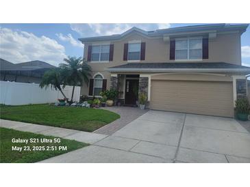 Two-story home featuring a manicured lawn, two-car garage, and stone pillar accents at 10549 Cypress Trail Dr, Orlando, FL 32825