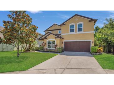 Two-story tan home featuring a well-manicured lawn and attached two-car garage at 15659 Carina Dr, Orlando, FL 32828