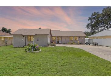 Charming single-story home with a well-maintained lawn and colorful flower garden at 27714 Lois Dr, Tavares, FL 32778