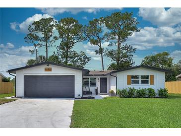 Charming one-story home featuring a gray garage door, manicured lawn, and neat landscaping at 550 Eagle Dr, Daytona Beach, FL 32117
