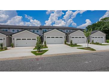 Row of modern townhomes, each featuring an attached single-car garage and manicured landscaping at 8584 Magnificent Ln, Groveland, FL 34736