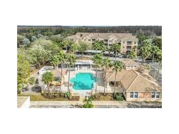 Beautiful aerial view of community pool with palm trees, clubhouse and condo building in a lush setting at 13512 Turtle Marsh Loop # 729, Orlando, FL 32837