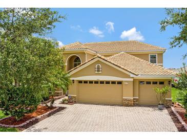 Beautiful two-story home featuring a neutral color scheme, tile roof, manicured landscaping, and a brick paver driveway at 2631 Captains Ct, Kissimmee, FL 34746