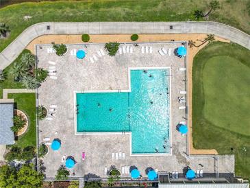Aerial view of the large community pool featuring plenty of lounge chairs and tables with umbrellas at 3944 Atrium Dr # 4, Orlando, FL 32822