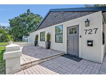 Charming home featuring a brick paver patio and stylish gray front door with decorative glass panel and sconce at 727 Seminole Ave, Orlando, FL 32804